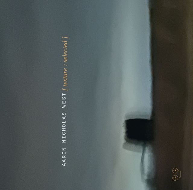 Cassette cover for [ texture : selected ]: a blurred grey-blue wall with a dark shape near a doorway, the name Aaron Nicholas West set vertically