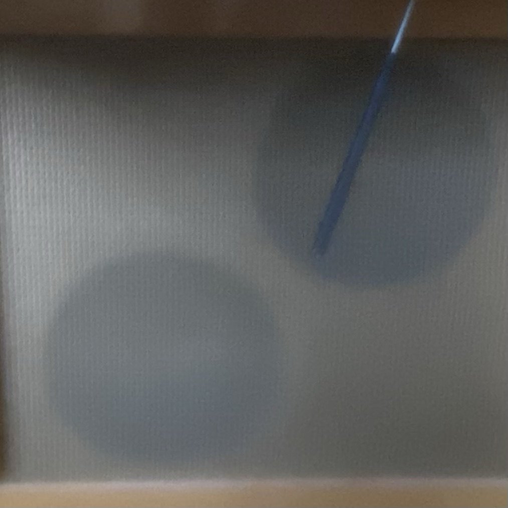 Soft grey-blue circular shadows on a fine ribbed surface, with one thin blue streak angled across the upper right