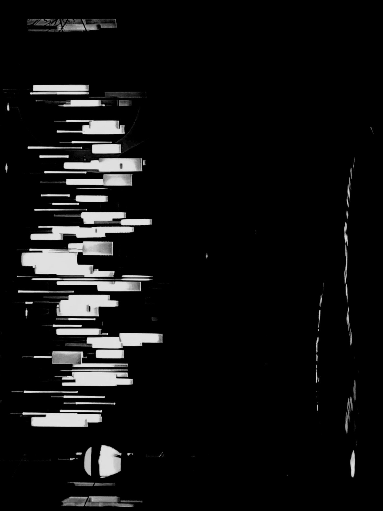 Abstract black-and-white image of pale rectangular shapes in staggered horizontal rows floating in solid black, like piano keys or blocks of tape seen sideways
